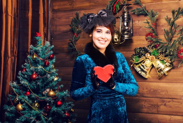 Διακοπές, γιορτή και άνθρωποι έννοια - χαμογελαστή γυναίκα με φόρεμα εκμετάλλευση κόκκινο δώρο πλαίσιο πέρα από το χριστουγεννιάτικο δέντρο φώτα υπόβαθρο — Φωτογραφία Αρχείου