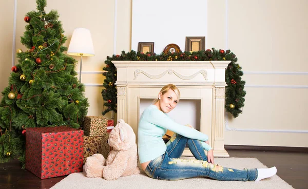 泰迪熊在圣诞装饰房子室内壁炉旁的年轻女子 — 图库照片