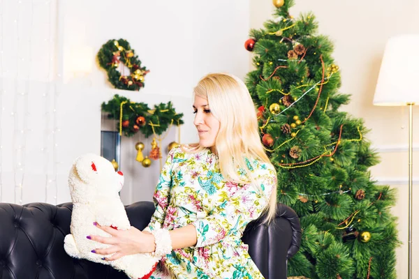 Schöne Frau am Weihnachtsbaum mit Teddybär — Stockfoto