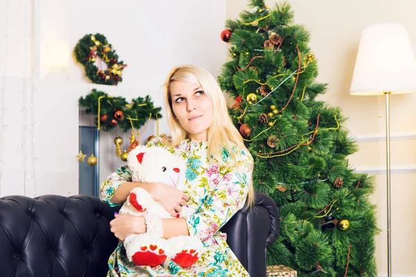 Όμορφη γυναίκα κοντά το χριστουγεννιάτικο δέντρο με αρκουδάκι — Φωτογραφία Αρχείου