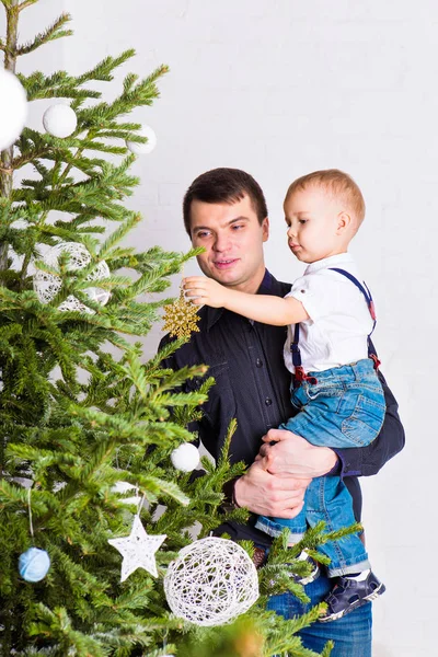 Familie, vakantie en Kerstmis concept - vader en zoon in de buurt van de kerstboom — Stockfoto