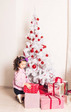 çocuk beyaz Noel ağacının yanında hediye kutusu