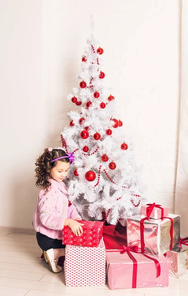 Criança com caixa de presente perto da árvore de Natal branca — Fotografia de Stock