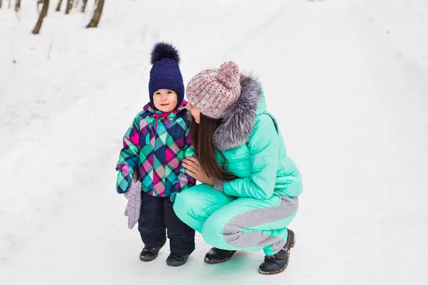 Família feliz mãe e bebê menina filha brincando e rindo no inverno ao ar livre na neve — Fotografia de Stock