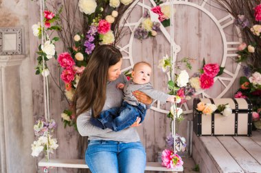 Yeni doğmuş çocuğunu tutan genç anne. Anne bakım bebek. Kadın ve yeni doğan çocuk odasında. Çocuk gülüyor ile oynarken annesi. Aile evde