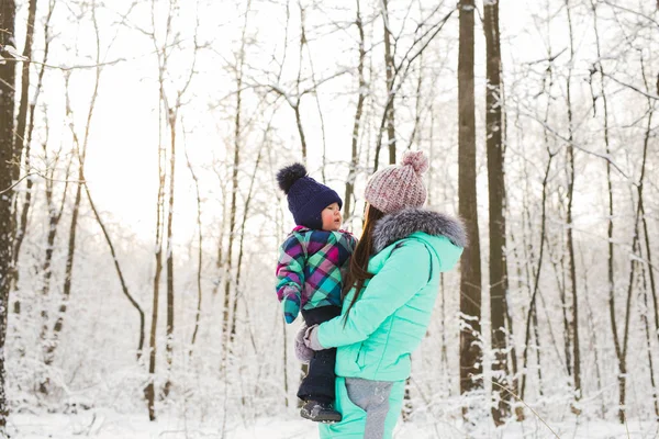 Happy mother and baby in winter park. family outdoors. cheerful mommy with her child — Stock Photo, Image