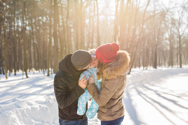 Happy young family with their baby son spending time outdoor in the winter park — Stock Photo, Image