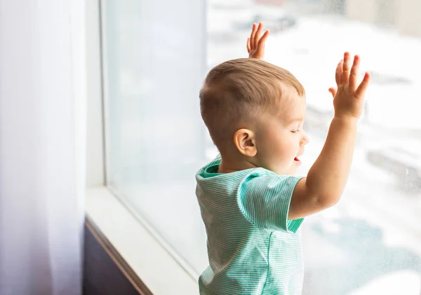 Liten pojke tittar genom fönstret. — Stockfoto