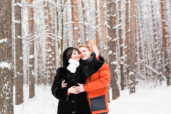 Koncepcji osób, sezonu, miłość, technologii i rekreacyjne - szczęśliwa para biorąc zdjęcie ze smartfonu na tle zima — Zdjęcie stockowe