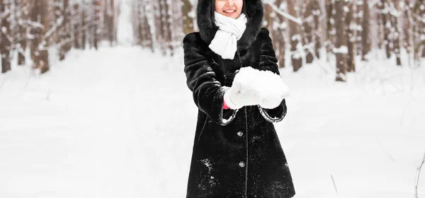 Primo piano della donna che tiene in mano la neve bianca morbida naturale per fare una palla di neve, sorridendo durante una fredda giornata invernale nella foresta, all'aperto . — Foto Stock