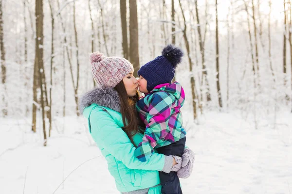 Glad familj mor och barn baby dotter på en vinter promenad i skogen — Stockfoto