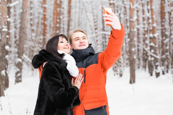 Para biorąc autoportret z inteligentny telefon w winter park. Piękna Młoda para selfie — Zdjęcie stockowe