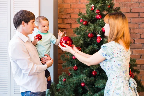 Szczęśliwa rodzina dekorowanie choinki z bombkami w salonie — Zdjęcie stockowe