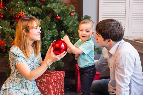 Koncepcja rodziny, Boże Narodzenie, x-mas, zima, szczęścia i ludzie - uśmiechający się rodziny z chłopca, siedząc pod drzewem xmas — Zdjęcie stockowe