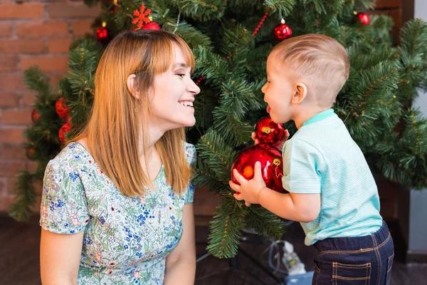 Mały chłopiec pomaga jego mama do dekoracji choinki. — Zdjęcie stockowe