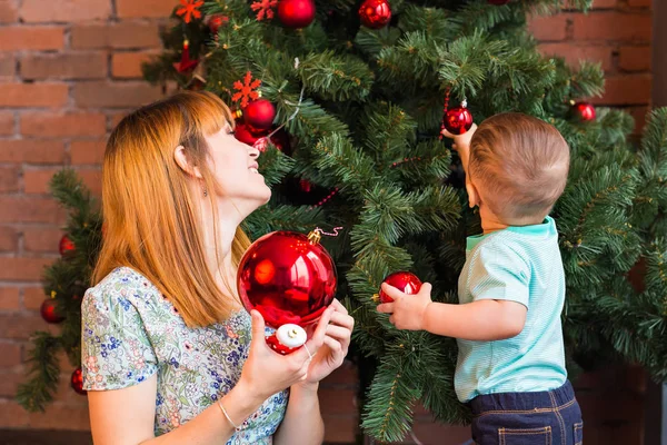Pequeño niño ayudando a su madre a decorar el árbol de Navidad . — Foto de Stock