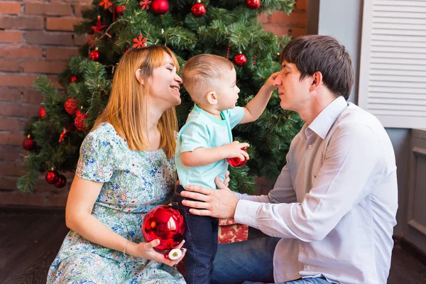Rodina, Vánoce, vánoční, zimní, štěstí a lidé koncept - usmívající se rodina s chlapeček sedící pod vánoční strom — Stock fotografie