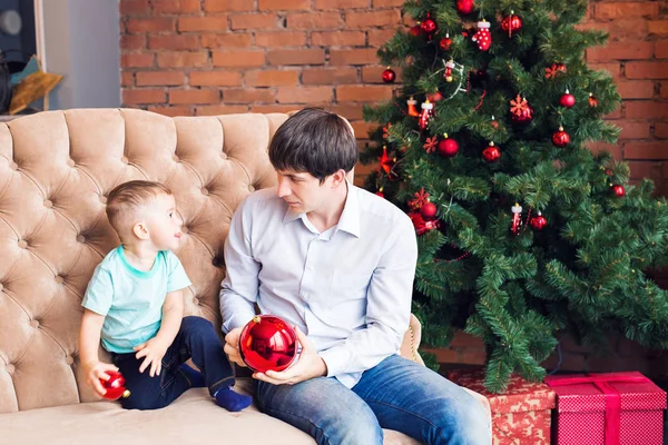 Feliz jovem pai brincando com seu filho bebê perto da árvore de Natal — Fotografia de Stock