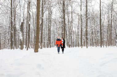 Mutlu çift kışın karlı bir ormanda yürüyor.