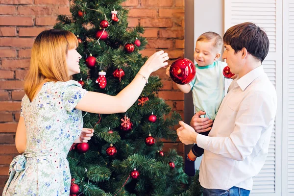 Happy Family Decorating Christmas Tree together. Father, Mother And Son. Cute Child. Kid