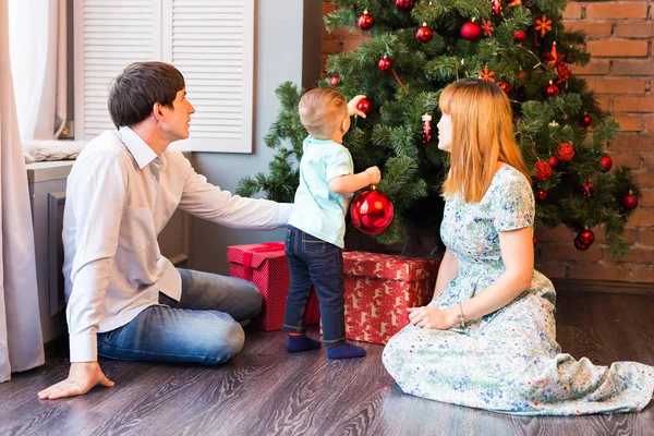 Feliz familia decorando el árbol de Navidad juntos. Padre, madre e hijo. Lindo niño. Niño. — Foto de Stock