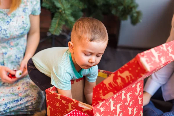 Портрет очаровательного мальчика с коробками подарков, заглядывающего в один из них — стоковое фото