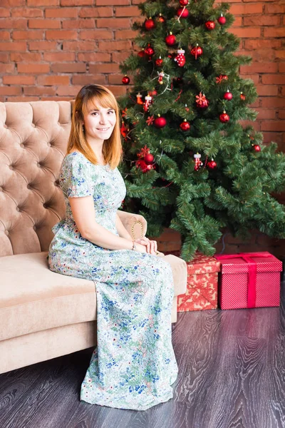 クリスマス ツリーのそばに座って幸せな若い女性の完全な長さの肖像画 — ストック写真