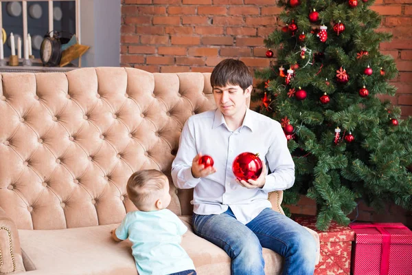 Feliz joven padre jugando con su hijo pequeño cerca del árbol de Navidad —  Fotos de Stock