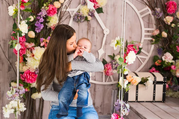 Madre joven sosteniendo a su hijo recién nacido. Mujer y bebé niño relajarse en un dormitorio blanco. Interior del vivero. Familia en casa — Foto de Stock