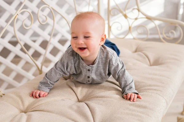 Adorable niño risueño en el dormitorio blanco y soleado. Niño recién nacido relajándose. Mañana familiar en casa . — Foto de Stock
