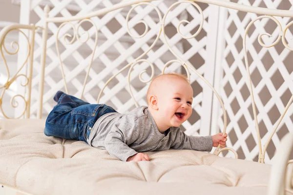 Adorable niño risueño en el dormitorio blanco y soleado. Niño recién nacido relajándose. Mañana familiar en casa . — Foto de Stock