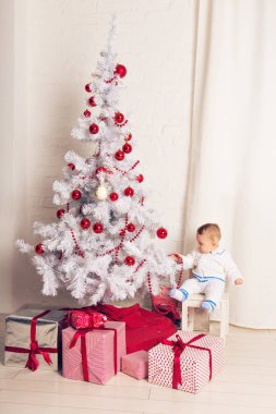 Noel ağacının yanında oynayan neşeli küçük oğlu