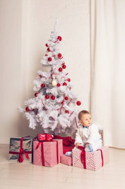 Noel ağacının yanında oynayan neşeli küçük oğlu
