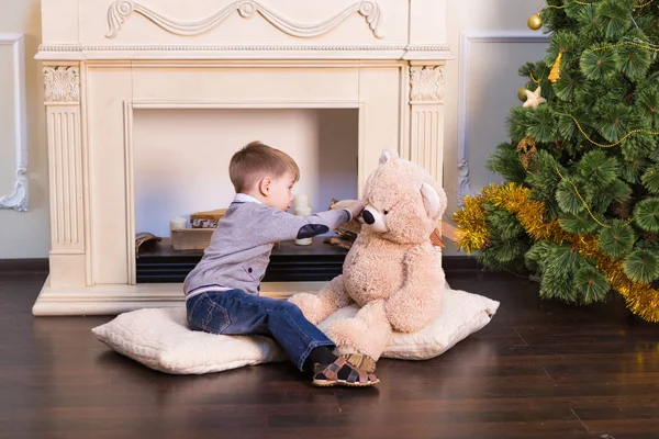 Chłopiec dziecko bawi się Pluszak Miś pod choinkę. — Zdjęcie stockowe