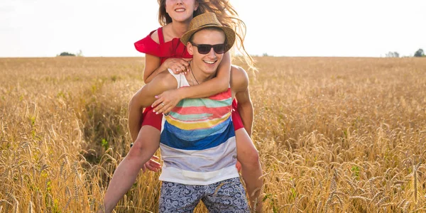 Gelukkig paar Having Fun buiten op tarweveld. Vrolijke familie lachen samen. Concept van de vrijheid. Meeliften — Stockfoto
