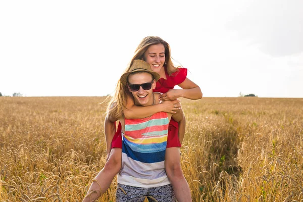 Gelukkig paar Having Fun buiten op tarweveld. Vrolijke familie lachen samen. Concept van de vrijheid. Meeliften — Stockfoto