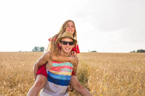 Casal feliz se divertindo ao ar livre no campo de trigo. Rindo Família alegre juntos. Conceito de Liberdade. Piggyback. — Fotografia de Stock