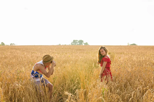 Erkek fotoğrafçı alanında duran genç bir kadının fotoğrafını çekmek. Çift doğa zevk gününde — Stok fotoğraf