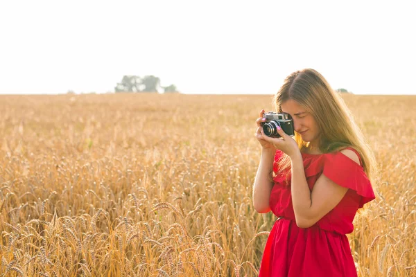 Fotógrafa femenina en el campo con una cámara tomando fotos —  Fotos de Stock