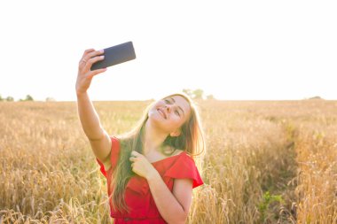 Sarı alan doğa arka plan ile selfie fotoğrafını alarak güzel bir kadın. Çekici bir genç gülümseyen kız portresi kapatın. Eğlenceli kavramı