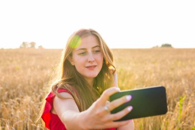 Sarı alan doğa arka plan ile selfie fotoğrafını alarak güzel bir kadın. Çekici bir genç gülümseyen kız portresi kapatın. Eğlenceli kavramı