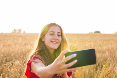 Sarı alan doğa arka plan ile selfie fotoğrafını alarak güzel bir kadın. Çekici bir genç gülümseyen kız portresi kapatın. Eğlenceli kavramı