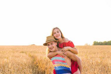 Mutlu çift sahip eğlenceli açık havada buğday alanında. Neşeli aile birlikte gülüyor. Özgürlük kavramı. Omzunda