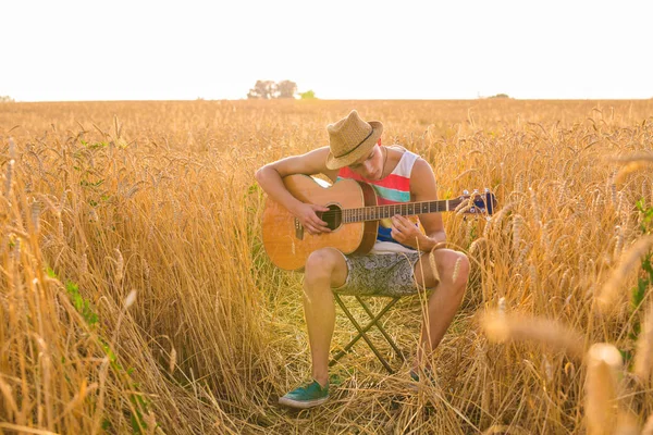 Jonge man speelt gitaar op het gebied — Stockfoto