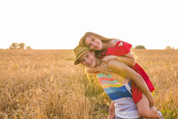 Casal feliz se divertindo ao ar livre no campo de trigo. Rindo Família alegre juntos. Conceito de Liberdade. Piggyback. — Fotografia de Stock