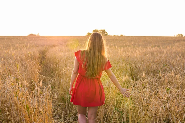 Chica vestida de rojo en el campo. Vista trasera —  Fotos de Stock