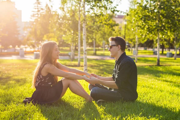 잔디에 앉아 공원에서 커플, 함께 좋은 시간을가지고 — 스톡 사진