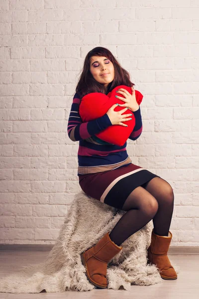 Linda mulher com travesseiro vermelho em forma de coração dentro de casa — Fotografia de Stock