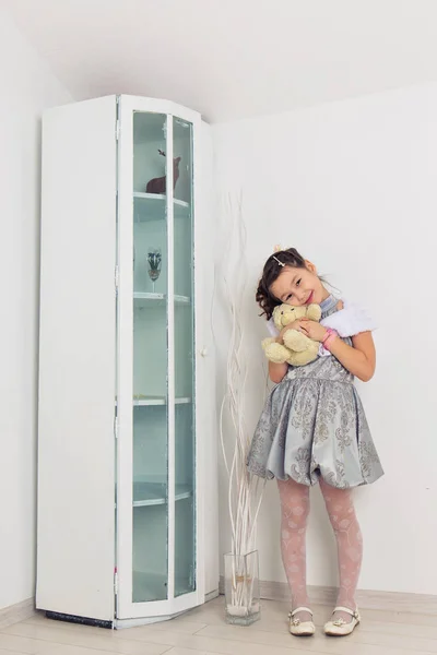 Schattig meisje knuffelen van een teddybeer. Schattige baby thuis in witte kamer. — Stockfoto