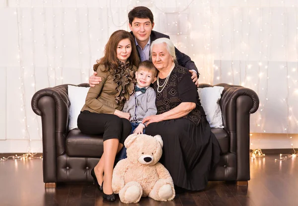 Rozšířená rodina sedí na gauči v obýváku a usmívá se na kameru — Stock fotografie